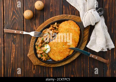 Poêle en fonte avec chanterelles frites, champignons au miel et crêpes aux pommes de terre à la sauce crémeuse Banque D'Images