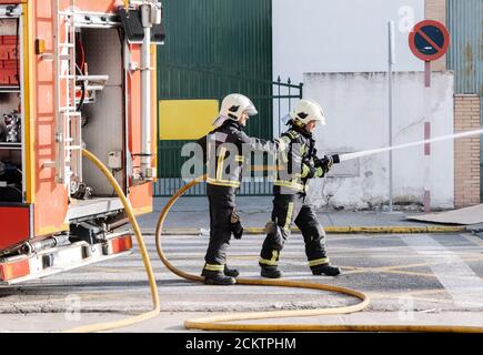 les pompiers avec un tuyau d'eau qui tire l'eau pour éteindre un incendie Banque D'Images