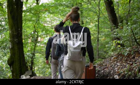 Les gars marchent le long des chemins de la forêt. Deux filles et un gars marchent dans le parc. Promenade le long des chemins de montagne. Banque D'Images