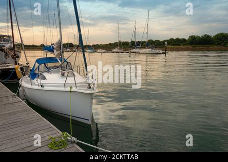 Yacht amarré sur un ponton en bois au crépuscule dans un cadre tranquille. Banque D'Images