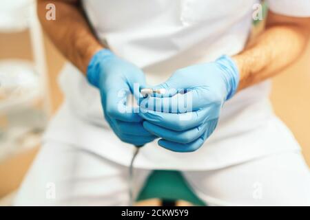 Gros plan des mains de dentistes tenant l'outil dentaire Banque D'Images