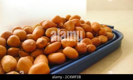 Arachides organiques indiennes isolées sur un bouchon de récipient bleu à surface plate avec foyer sélectif. Banque D'Images