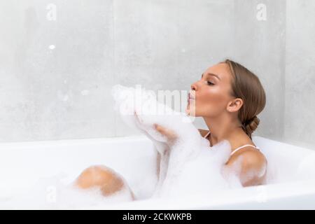 Portrait d'une jeune femme jouant avec de la mousse dans la baignoire Banque D'Images