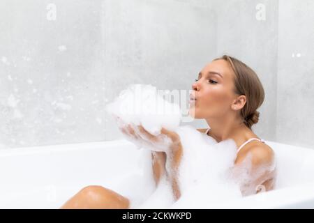 Portrait d'une jeune femme jouant avec de la mousse dans la baignoire Banque D'Images