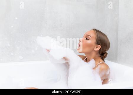 Portrait d'une jeune femme jouant avec de la mousse dans la baignoire Banque D'Images