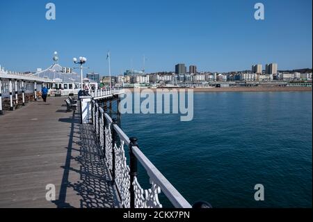 Vue sur le front de mer de Brighton depuis la jetée du Palace lors d'une journée ensoleillée avec les touristes qui s'amusant à se promener le long de la jetée. Banque D'Images