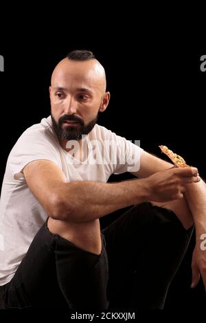 Jeune ouvrier de construction hispanique mangeant de la pizza Banque D'Images