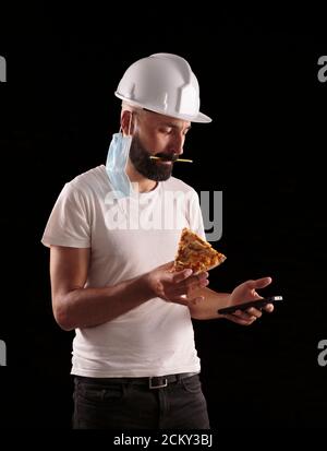 Un jeune ouvrier de construction hispanique vérifie son téléphone pendant le déjeuner Banque D'Images
