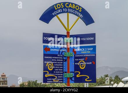 Cabo San Lucas, Mexique - 22 avril 2008 : gros plan du panneau directionnel bleu avec des noms jaunes et blancs d'entreprises en ville contre le ciel bleu clair. Mo Banque D'Images