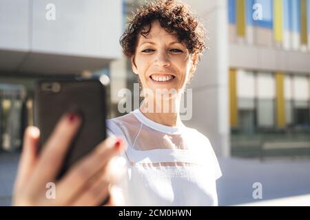 Souriante, jeune femme touriste qui prend le selfie dans la ville sous le soleil jour pendant les vacances Banque D'Images