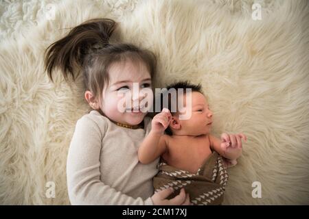 La grande sœur embrasse le nouveau-né frère tout en posant sur Fuzzy Rug Banque D'Images