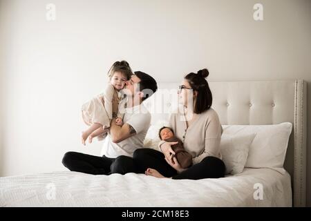 Le père millénaire Kisses, fille très petite, assis en famille Banque D'Images