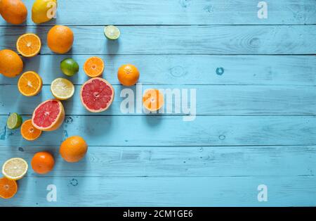 Trancheuse d'aliments crus et agrumes entiers, citron rouge orange, pamplemousse, citron vert placé sur le côté gauche sur un fond bleu en bois avec un espace d'imitation Banque D'Images