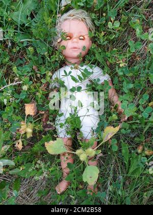 Triste enfant oublié concept de la poupée dans l'herbe. Le temps passe et l'enfance est laissée en arrière sans plus de temps pour jouer. Grunge sale craepy jouet t Banque D'Images