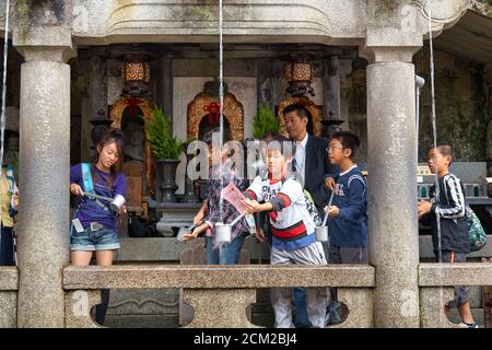 Kyoto, Japon - 23 novembre 2007 : les étudiants de la cascade d'Otowa attrapent l'eau de l'un des trois cours d'eau distincts pour la santé, la longévité et Banque D'Images