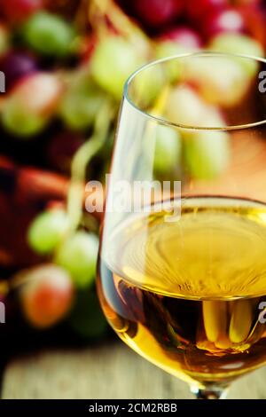 Vin blanc dans un verre de raisin d'automne, vieux fond en bois, foyer sélectif Banque D'Images