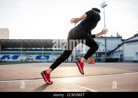 Athlète masculin de vêtements noirs à partir sprint sur une piste de course Banque D'Images