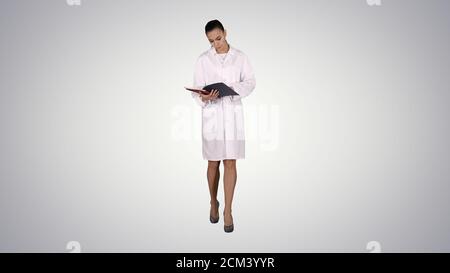 Jeune médecin femme lisant la documentation tout en marchant sur le gradient Banque D'Images