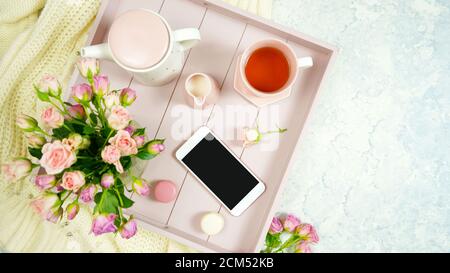 Décor rose blush espace de travail confortable avec clavier smartphone thé et rose sur un élégant fond texturé en marbre blanc. Vue de dessus de blog héros Banque D'Images
