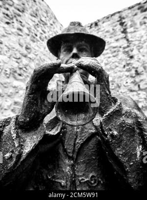 Statue en bronze d'un musicien traditionnel jouant un instrument de vent typique appelé 'Dullzaina' devant un mur lapidé à Burgos, en Espagne. Banque D'Images