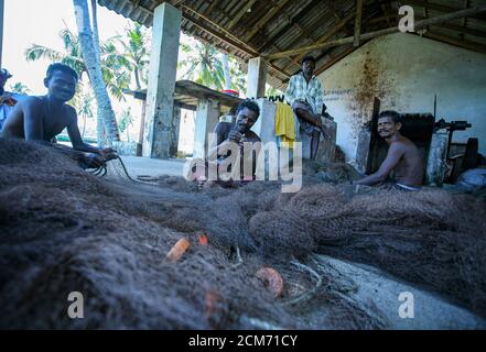 La vie des pêcheurs traditionnels au Kerala, bateau de pêche en bois, pêcheur jetant le filet dans le rivage, pêcheur répare le filet de pêche, Banque D'Images