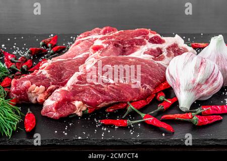 Steak de viande cru non cuit striploin New york sur un panneau de pierre avec poivre et romarin, vue latérale, horizontal Banque D'Images