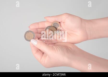 La femme considère les pièces en euros. Seules les mains et l'argent sont visibles. Sur fond gris Banque D'Images