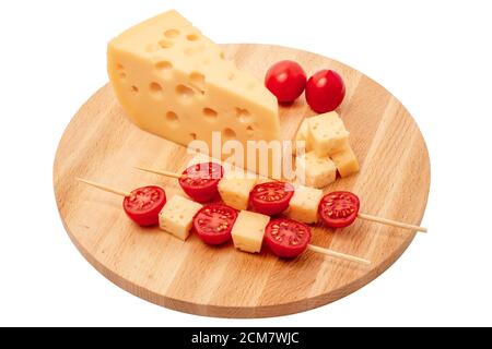 morceau de fromage et brochettes de fromage à la tomate sur une planche en bois, pièce de fromage triangulaire, fromage avec trous découpés sur fond blanc Banque D'Images