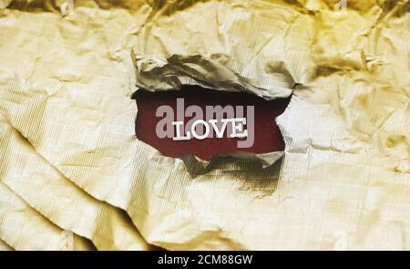l'amour de l'inscription est vu sous le papier déchiré doré. Concept de relation Banque D'Images