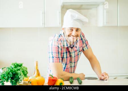 Jeune homme hacher les légumes dans la cuisine Banque D'Images