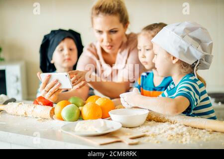 Mère et fille dans des robes avec téléphone. Sur la cuisine Banque D'Images