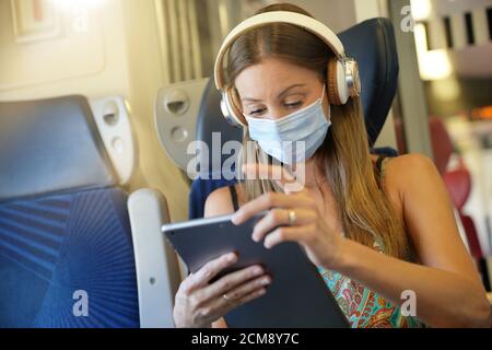 Jeune femme voyageant en train, portant un masque facial Banque D'Images