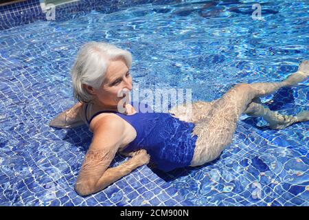 Femme âgée se détendant dans la piscine Banque D'Images