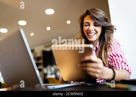 Bonne jeune femme qui reçoit de bonnes nouvelles sur sa tablette Banque D'Images