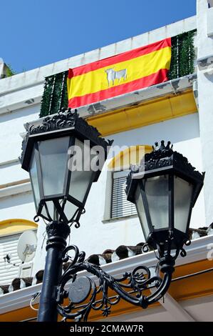 Lampadaire en fer forgé avec drapeau espagnol sur un balcon de maison de ville à l'arrière, Benahavis, Costa del sol, province de Malaga, Andalousie, Espagne. Banque D'Images