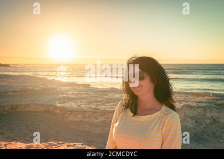 Femme sur la plage en admirant le coucher du soleil à Port Noarlunga, Australie méridionale Banque D'Images