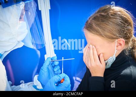 Prélèvement d'un échantillon médical - un écouvillon de gorge pour un test de coronavirus. L'infirmière prélève un échantillon de l'enfant blonde fille pour le test Covid 19. Une expérience désagréable Banque D'Images