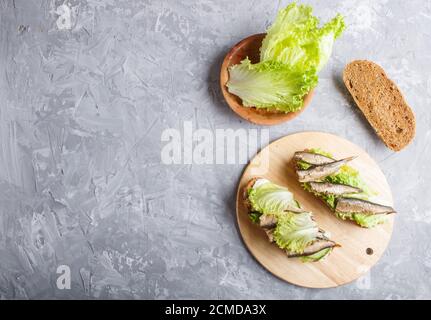 Sandwichs à base de laitue et de fromage à la crème, sur bois, sur fond de béton gris. Vue du dessus, espace pour les copies, plat. Banque D'Images