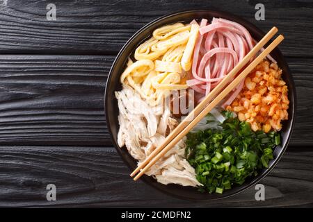 Soupe de nouilles Hanoi avec poulet, jambon, crevettes, œufs et herbes dans un bol sur la table. Vue horizontale du dessus Banque D'Images