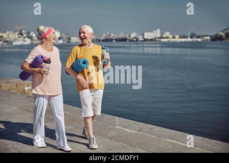 Joyeux retraités sportifs tenant des tapis roulés sous leurs bras Banque D'Images