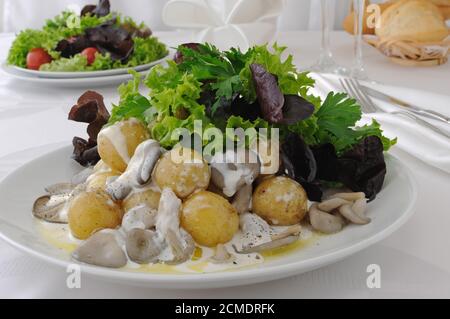 Pommes de boules avec des champignons et des feuilles de laitue dans une sauce à la crème Banque D'Images