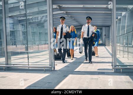 Équipage avec valises à pied dans le terminal de l'aéroport Banque D'Images