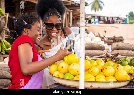 femme africaine vendant sur un marché et regardant un client contenu sur un téléphone Banque D'Images