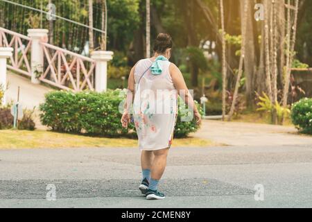 Vue arrière d'une femme asiatique âgée porte un écouteur pour écouter la marche de chant et le jogging pour une bonne santé dans le parc public.jogging senior dans la nature. Plus ancien Banque D'Images