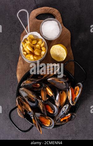 Des moussels et des frites ou des grains de beauté sur ardoise noire. Cuisine belge typique. Banque D'Images