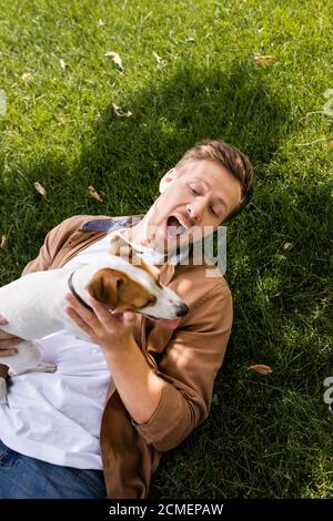 vue de dessus de l'homme excité couché sur une pelouse verte avec jack russell chien terrier Banque D'Images