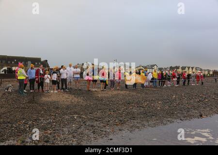 Prestwick, Ayrshire, Écosse, Royaume-Uni 26 décembre 2017 : lorsque la Maison Malcolm Sargent, dirigée par l'organisme de bienfaisance Clic Sargent, a fermé un groupe de bénévoles et de partisans de l'organisme de bienfaisance ont décidé d'essayer de sauver la propriété et de l'acheter. L'un des événements de collecte de fonds a été un plongeon le lendemain de Noël dans la mer à Prestwick. Se préparer à courir dans la mer Banque D'Images