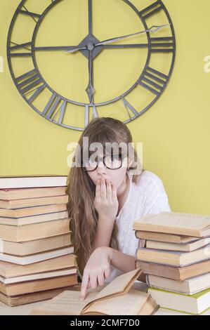 Fille avec des verres lire le livre quelque chose d'étonnant. Banque D'Images