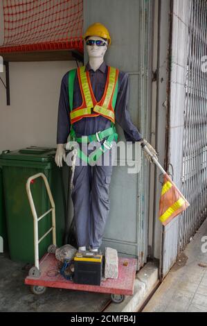 Mannequins d'un travailleur à l'extérieur sur une brouette avec batterie de voiture à l'avant, affiche le mannequin. Banque D'Images