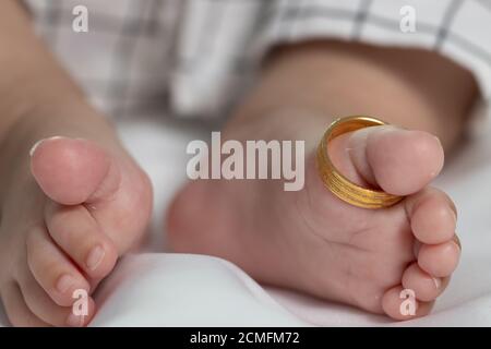 Anneaux de mariage sur les petites jambes d'un nouveau-né. Banque D'Images